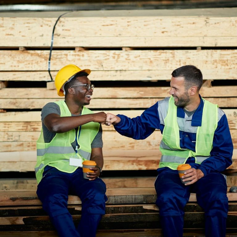alternance Deux travailleurs sur un chantier, se serrant la main, souriant et portant des gilets de sécurité.