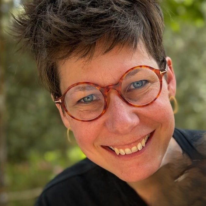 Femme souriante portant des lunettes au style rétro, en extérieur.