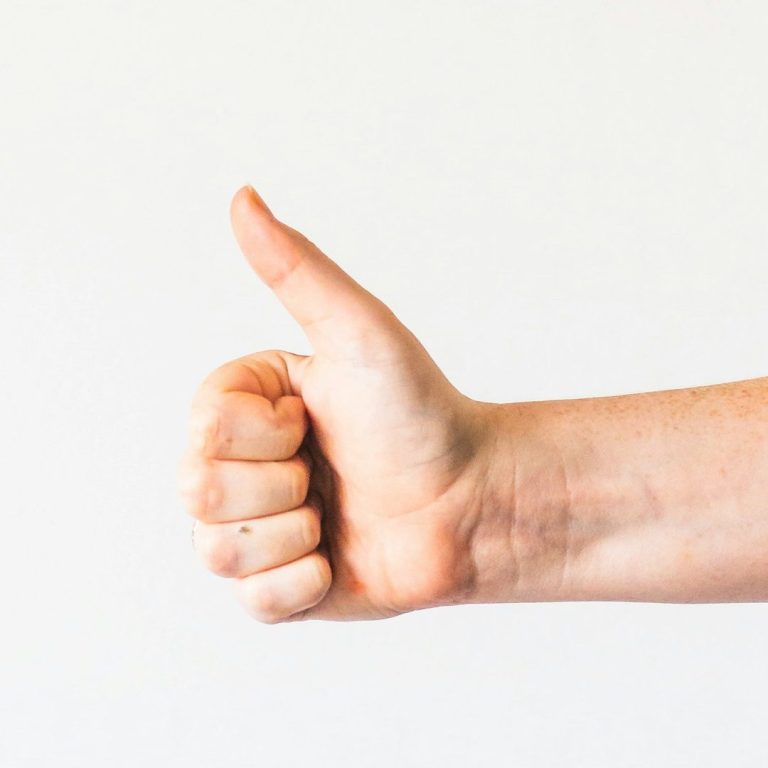 Main levée avec un pouce remonté, symbole de satisfaction ou d'approbation.